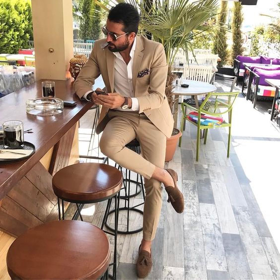 A beige suit a white button down brown moccasins to create a stylish and chic wedding guest look