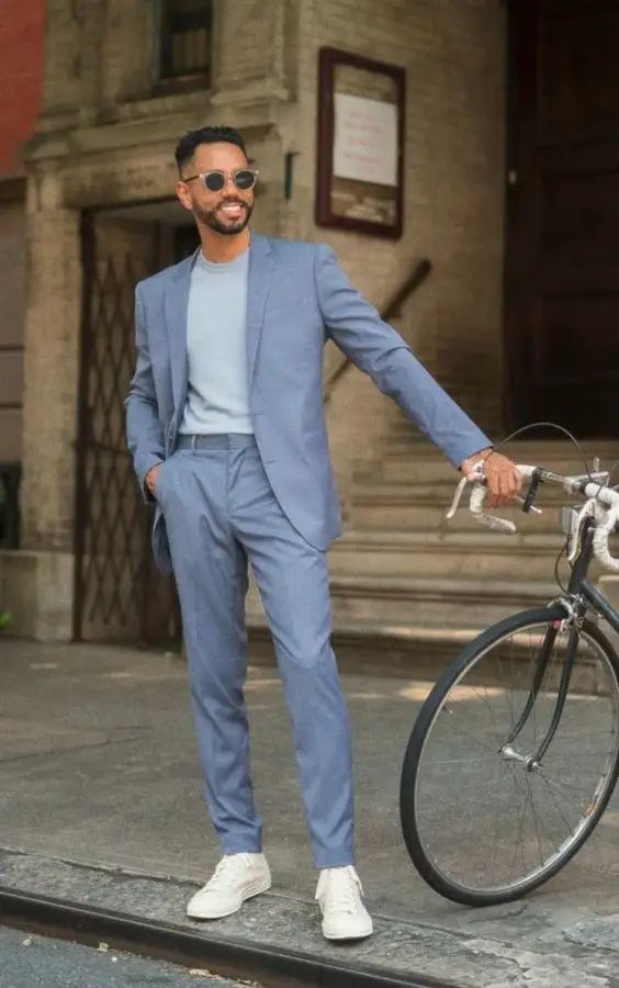 A blue suit a light blue t shirt white sneakers for a stylish modern look at a spring or summer wedding