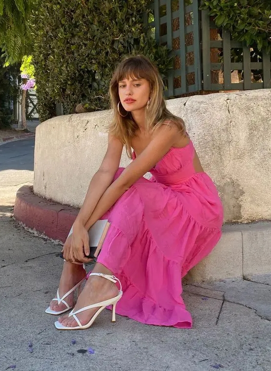 A classy and girlish pink strapless dress with a cutout back plus white strappy heels and hoop earrings for the summer or beaches