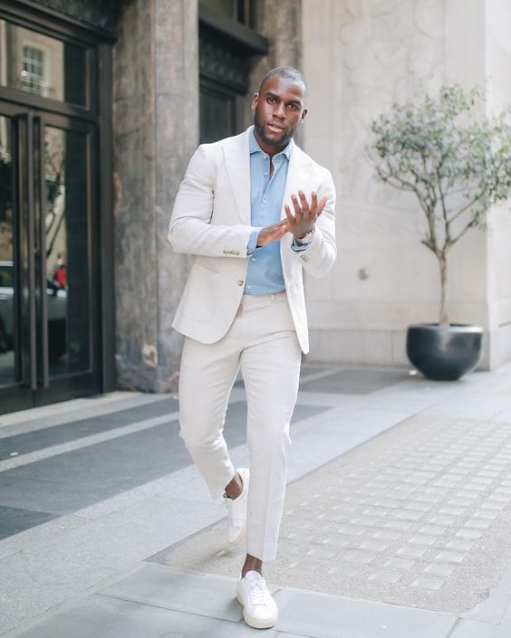 A classy outfit with a creamy suit a blue button down white sneakers is a cool solution for a summer celebration