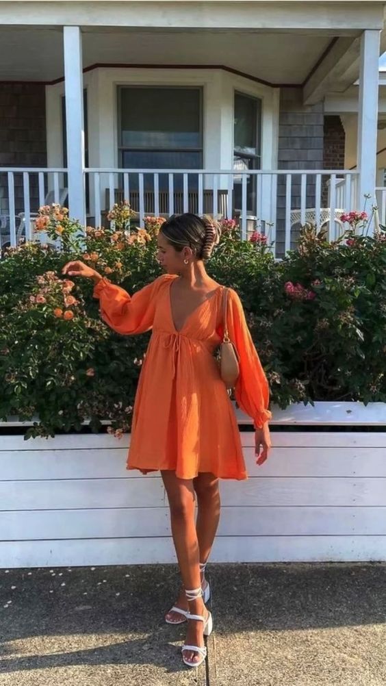 A comfortable orange mini dress with a deep neckline and long sleeves lace up shoes and a nude bag