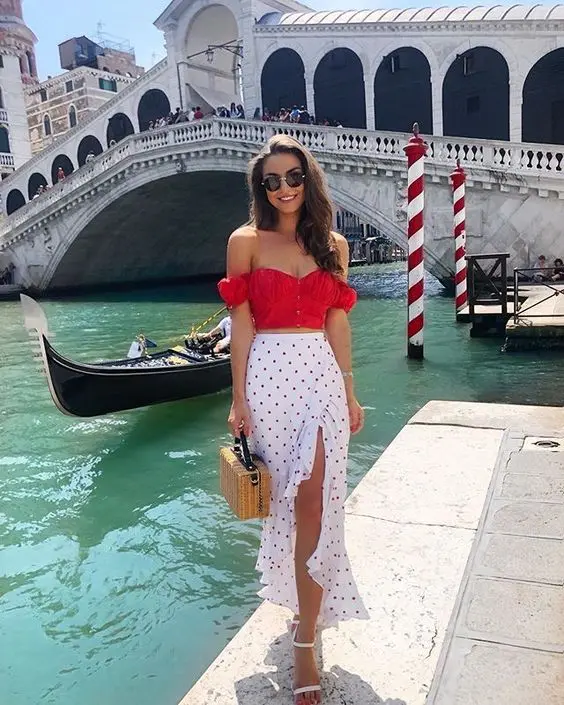 A romantic summer outfit with a red off the shoulder top a polka dot midi skirt with ruffles and white shoes