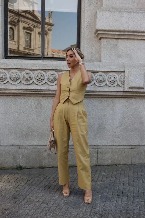 A summer bridal shower look with a yellow linen suit with a vest and pants nude shoes a small nude bag
