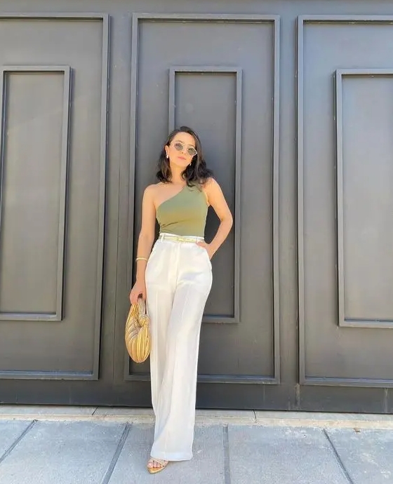 This breezy look with a green one shoulder top white linen palazzo pants tan sandals and a neutral mini bag is great for the summer