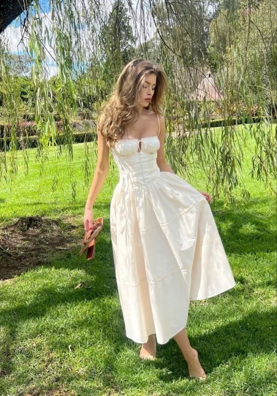 a neutral A line midi dress with spaghetti straps and a pleated skirt looks romantic and charming