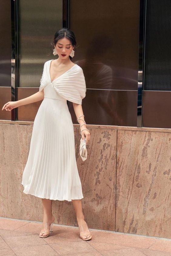 a sophisticated pleated midi dress with plated sleeves and a skirt clear shoes and a small bag plus chic jewelry